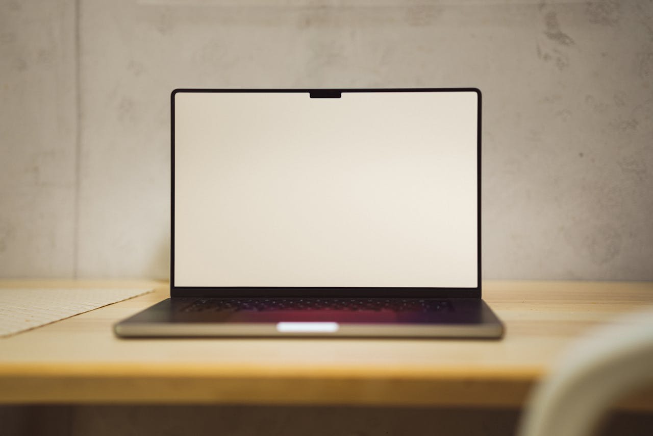 Explore a serene workspace setup featuring an open laptop on a wooden desk, perfect for modern design themes.
